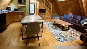 Une pièce confortable de style loft, comprenant un coin repas, un canapé et un escalier menant à un niveau supérieur.