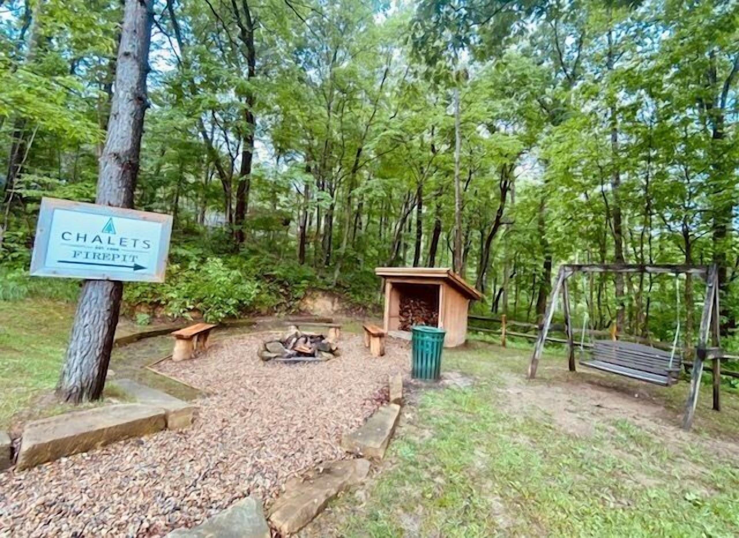 Ein bewaldetes Gebiet mit einem Schild, das 'Chalets Firepit' anzeigt.