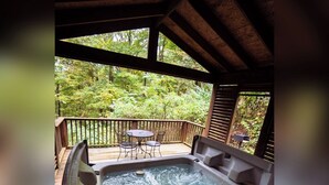A hot tub on a wooden deck with a view of a forest. - A-Frame #03 - Hosted by The Chalets (Logan)