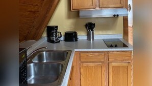 Une cuisine compacte avec des meubles en bois, un évier en acier inoxydable, une machine à café et un grille-pain.