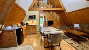 Une pièce confortable de style loft, dotée d’un escalier en bois, d’un coin repas et d’une petite cuisine.
