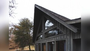 Ein Holzhaus mit Veranda, großen Fenstern und einem Geländer.