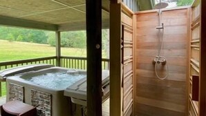 Eine Holzterrasse mit Whirlpool und einer Holzzause.