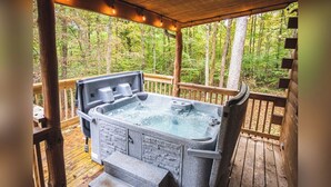 Un bain à remous sur une terrasse en bois, avec vue sur une forêt.