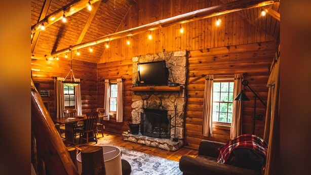 L’intérieur d’un chalet confortable, avec une cheminée en pierre, des murs en bois et un coin repas.