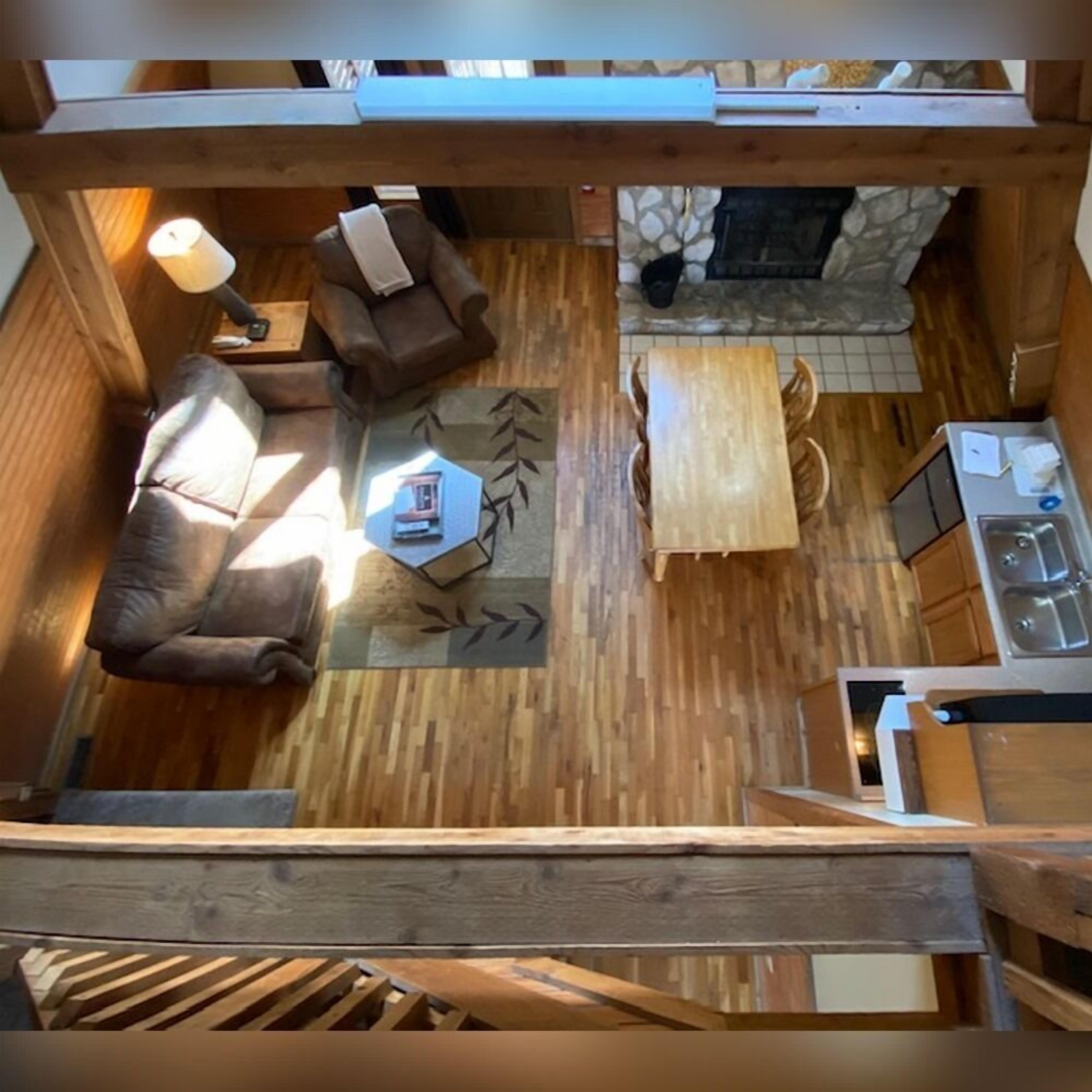Une petite cabane en bois comprenant un espace de vie, une table à manger, un canapé et une cuisine.