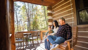 Eine Holzterrasse mit Schaukel, Holzstühlen und einem Tisch.