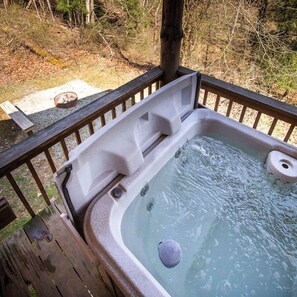 Ein Whirlpool mit einer Holzterrasse und Geländern, eingebettet in eine natürliche Umgebung.