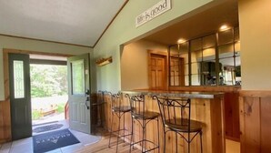 Una cocina con armarios de madera, una zona de bar con taburetes y un cartel sobre el bar que dice 'Life is good'.