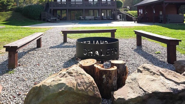 Un lodge rústico con un gran pozo de fuego en el centro, rodeado de bancos y grandes rocas.