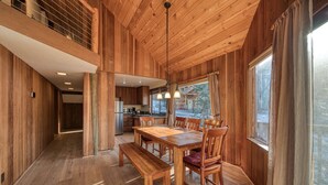 Un interior de madera con comedor, cocina y ventanas amplias.