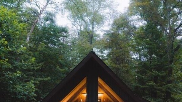 A cabin with a large deck, a dining area, and a visible kitchen. - Laurelwood - Hosted by The Chalets (Logan)