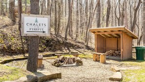 Schild für Chalets Firepit mit einer Holzunterstand und Holzscheiten in der Nähe.