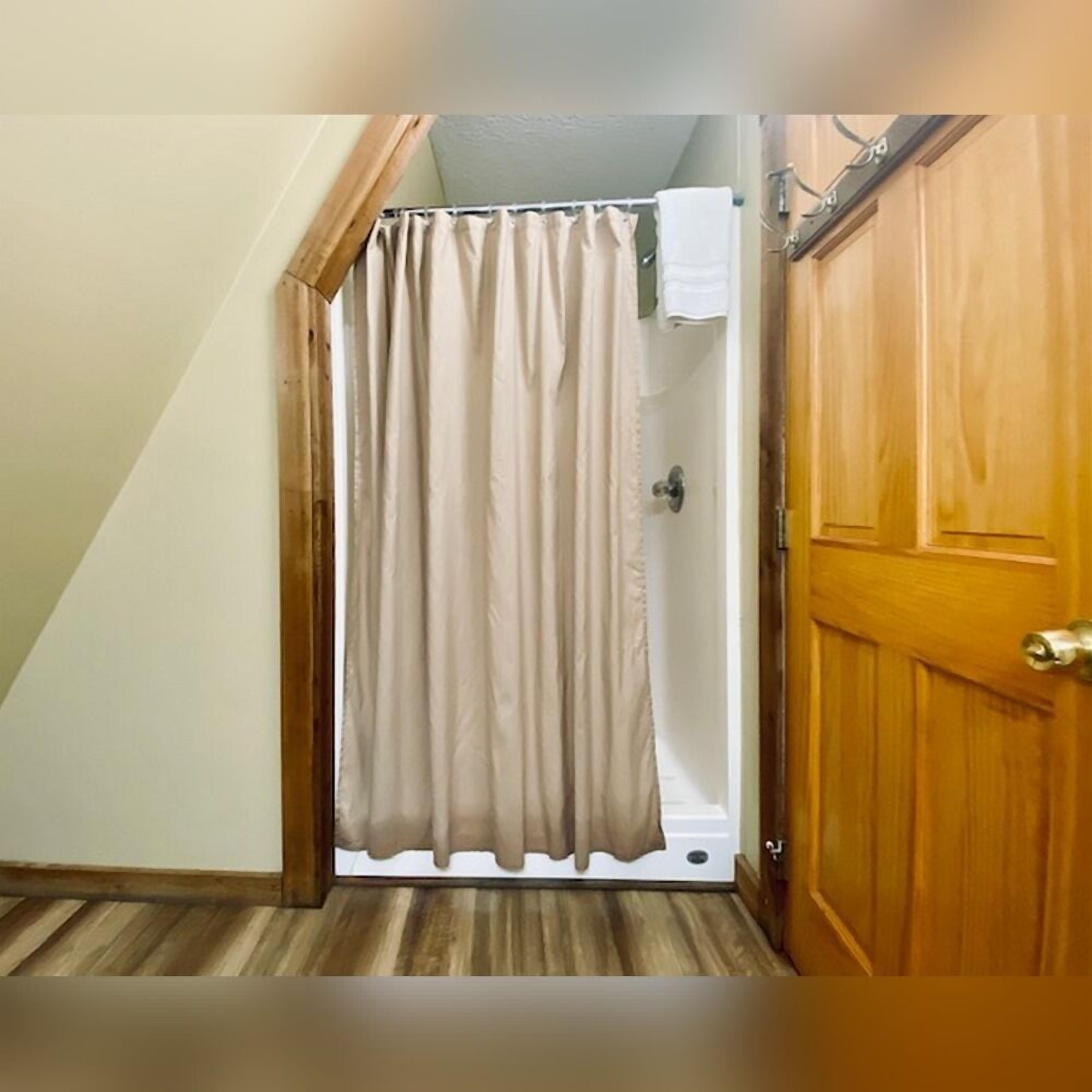 Ein schmales Entree mit einer Holztür rechts und einem beige farbenen Vorhang links.
