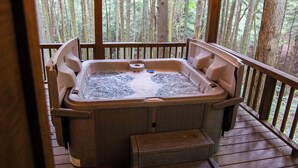 A hot tub on a wooden deck with a view of a forest. - The Ravine - Hosted by The Chalets (Logan)