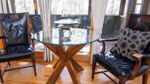A room with two leather chairs, a glass table, and a view through large windows. - The Ravine - Hosted by The Chalets (Logan)