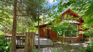Eine Holzhütte mit Veranda, umgeben von Bäumen und einem Steinweg.