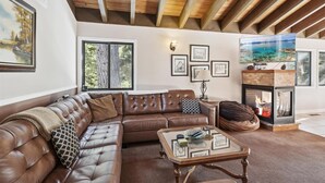 A spacious living room with a leather sectional sofa, a glass coffee table, and a fireplace. - On the Edge at Alpine By Tahoe Getaways - Dog OK- Mountain Views- Ski Shuttle! (Alpine Meadows)