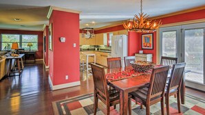 A spacious dining area with a wooden table and chairs, a chandelier, and a view of the kitchen and living room. - Pottsboro Home on 2 Acres w/ Hot Tub, Near Marina! (Pottsboro)