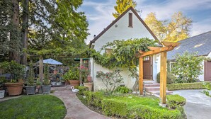 Una casa con jardín, una pérgola de madera y una estatua de cisne.