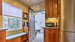 Una cocina compacta con armarios de madera, un banco integrado, un refrigerador de acero inoxidable y un microondas.