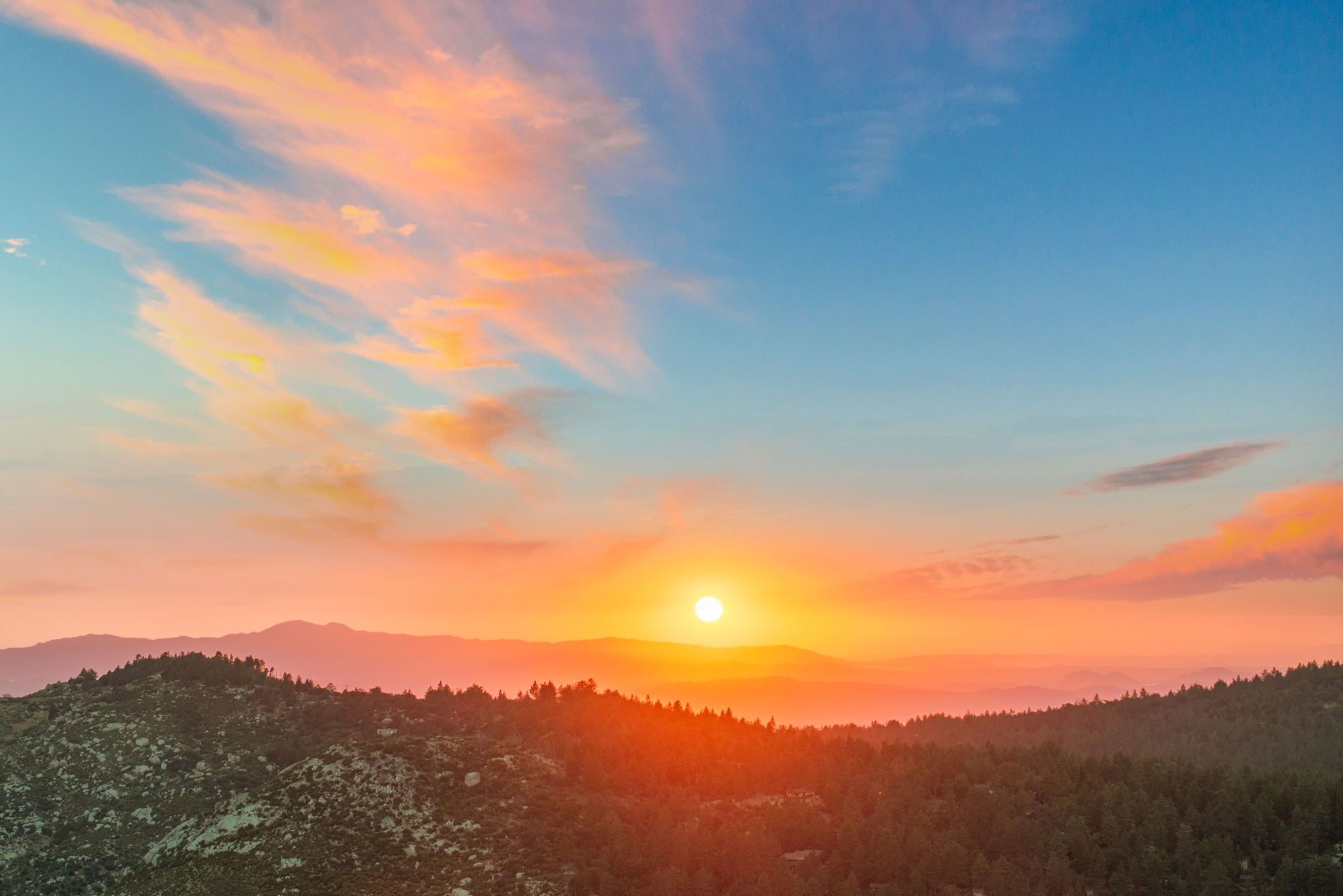 Un atardecer sobre un paisaje montañoso bajo un cielo despejado.