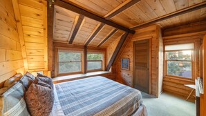 Un dormitorio de cabaña de madera acogedor, con cama, almohadas y ventana.