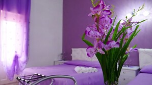 Una habitación con una cama morada, una mesita de noche y una silla.
