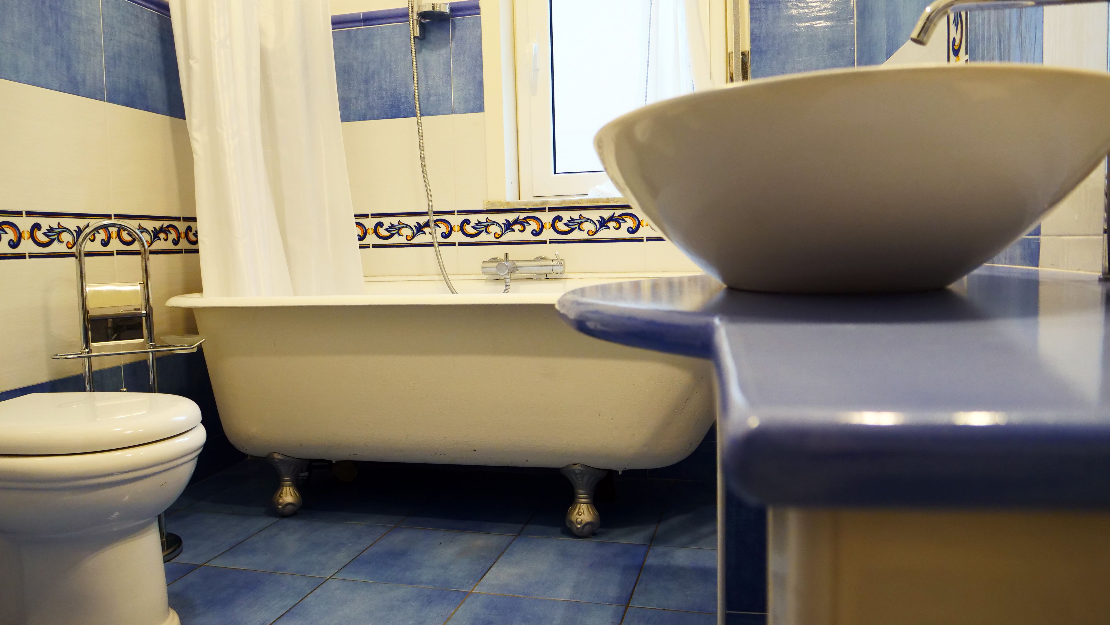 Een badkamer met toilet, een ligbad op pootjes en een wastafel.