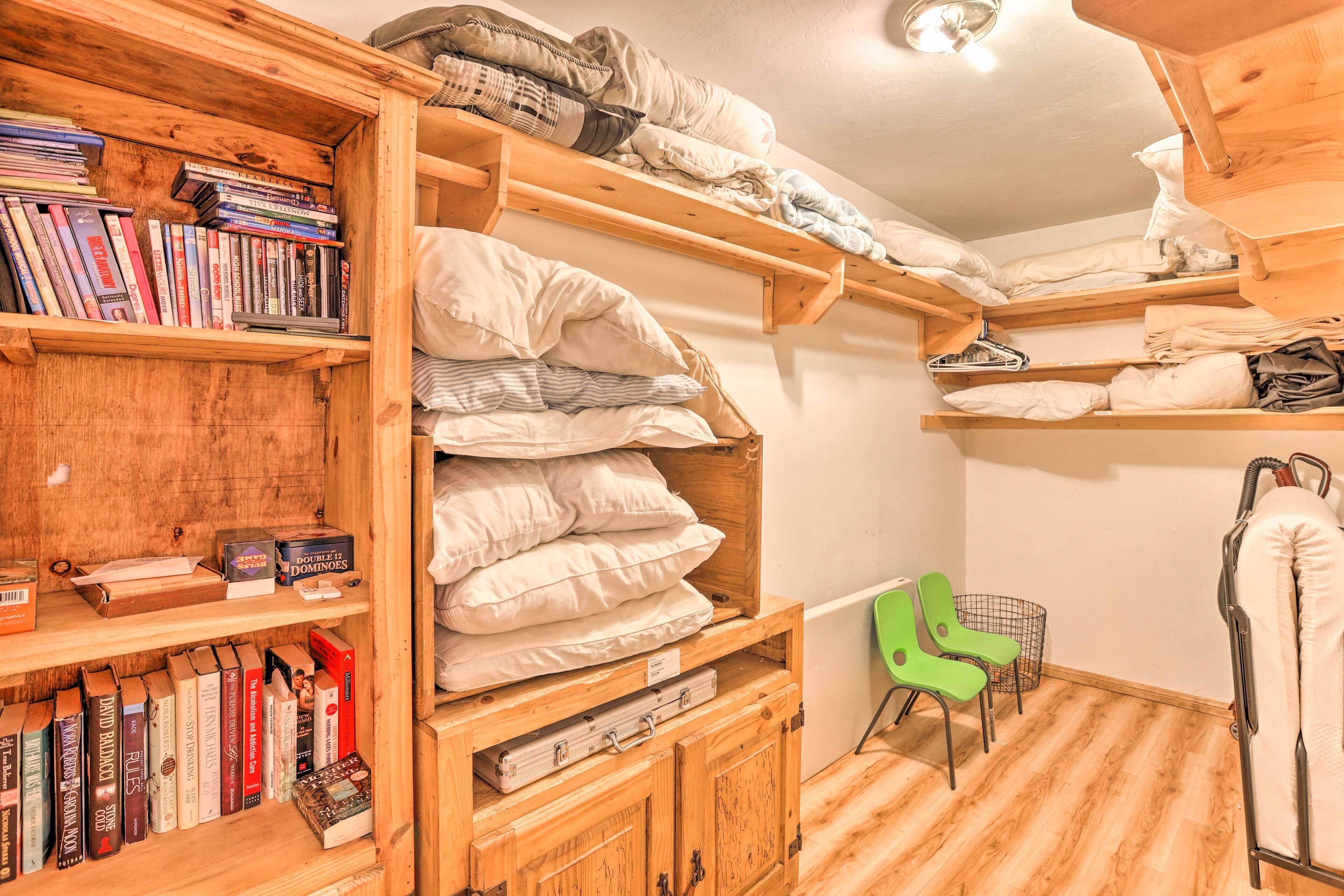 Ein Zimmer mit Holzböden, Bücher und Kissen, einem grünen Sessel und einem Metallgestell mit einem Handtuch.