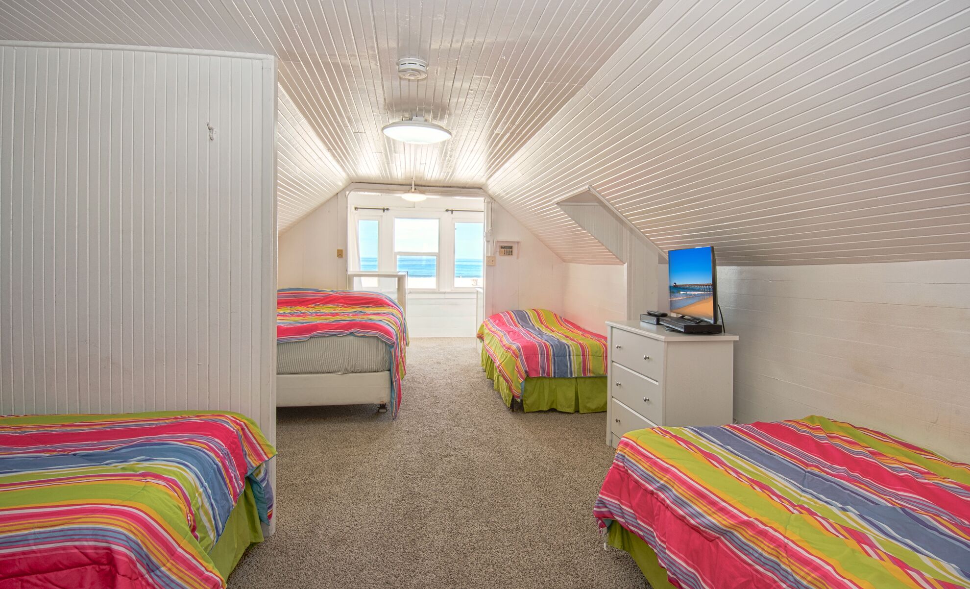 Une chambre avec deux lits, une commode et un téléviseur.