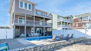 A multi-story residential building with a pool, outdoor seating, and a fenced patio area. - Shorenuff - Nags Head MP 11, Ocean View, Beach 200 Yds, Pool, Hot Tub, Pool Table, YR Flex Stays (Nags Head)
