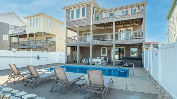 A two-story building with a balcony, a swimming pool, and outdoor seating. - Shorenuff - Nags Head MP 11, Ocean View, Beach 200 Yds, Pool, Hot Tub, Pool Table, YR Flex Stays (Nags Head)