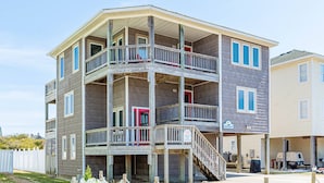 A multi-story building with balconies, a covered porch, and a sign indicating it is for rent. - Shorenuff - Nags Head MP 11, Ocean View, Beach 200 Yds, Pool, Hot Tub, Pool Table, YR Flex Stays (Nags Head)