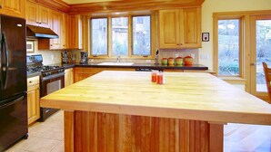 Une cuisine spacieuse avec des meubles en bois, un grand îlot central et une vue sur un paysage enneigé par les fenêtres.