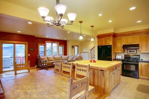 A spacious kitchen with wooden cabinets, a central island, and a dining area with chairs.