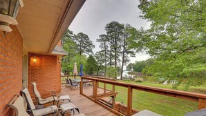 A wooden deck with outdoor seating, a view of a lake, and a brick wall. - 'River's Edge Retreat’ with Kayaks & River Access! (Reedville)