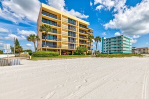 Un hotel de varios pisos con balcones, un estacionamiento y una playa al frente.