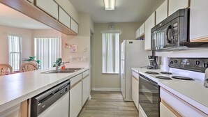 Una cocina compacta equipada con lavavajillas, estufa, microondas y refrigerador.