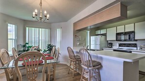 Una cocina moderna con una isla central, sillas de madera y una mesa de comedor.
