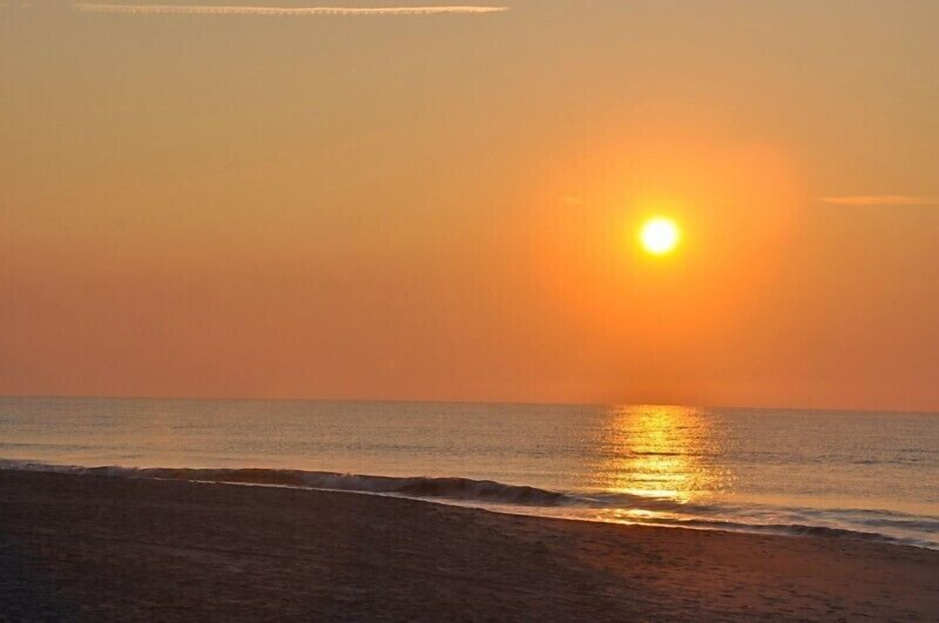 Un coucher de soleil sur une plage aux eaux calmes.