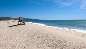 Ein Strand mit einem Rettungsturm, feinem Sand und dem Meer.