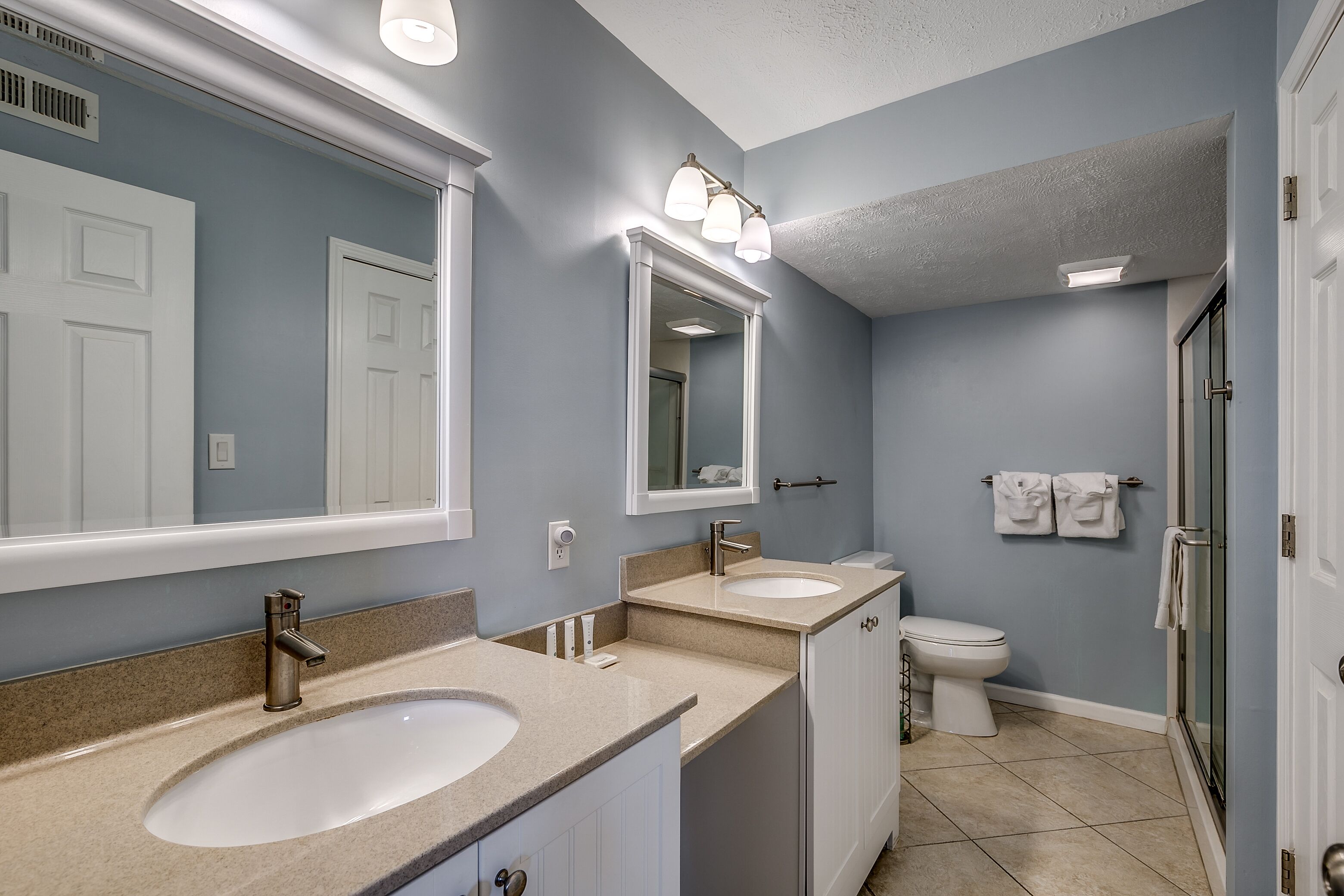 A bathroom with two sinks, a toilet, and a shower area.