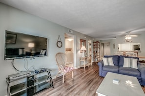 A living room with a flat-screen TV, a sofa, a coffee table, and a dining area with a table and chairs. - ☀️ Ocean Front - Private Balcony - Anchorage II 215 ☀️ (Myrtle Beach)