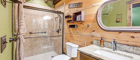 Une salle de bain avec une douche à parois de verre, des toilettes, un lavabo avec un plan de travail en granit et un lambris en bois.