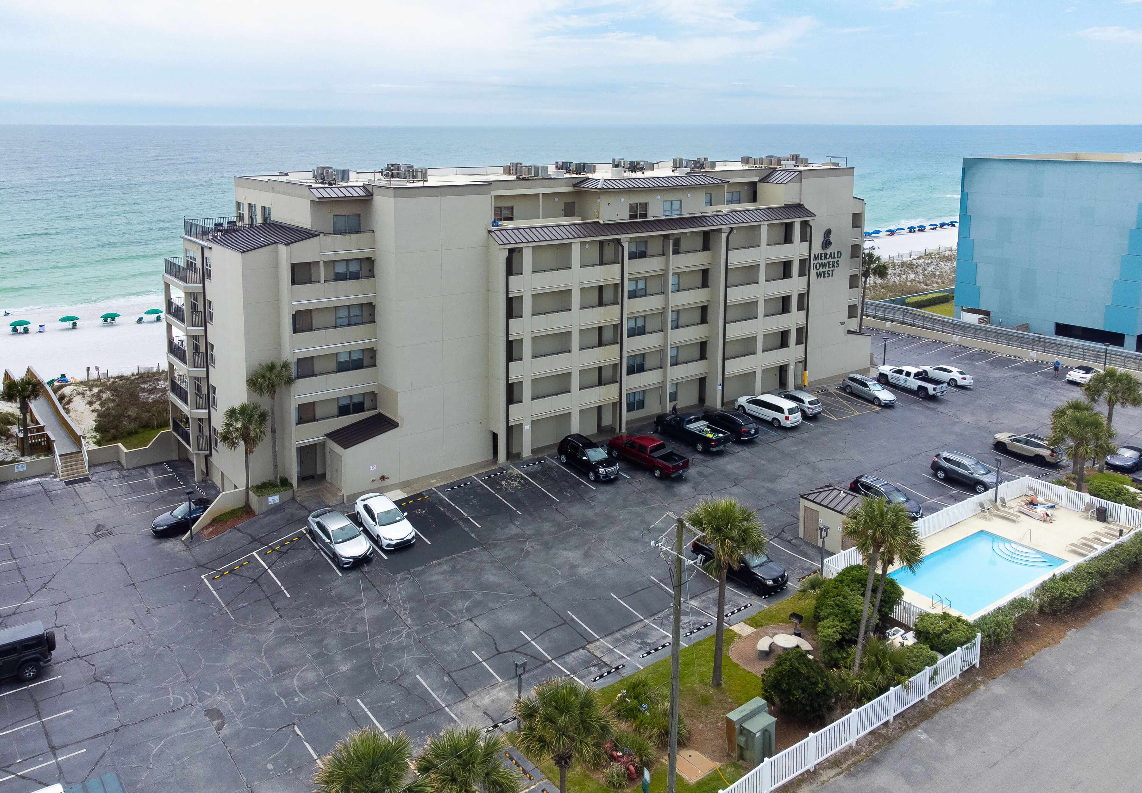 Un hôtel à plusieurs étages doté d’un parking, d’une piscine et offrant une vue sur la plage et l’océan.