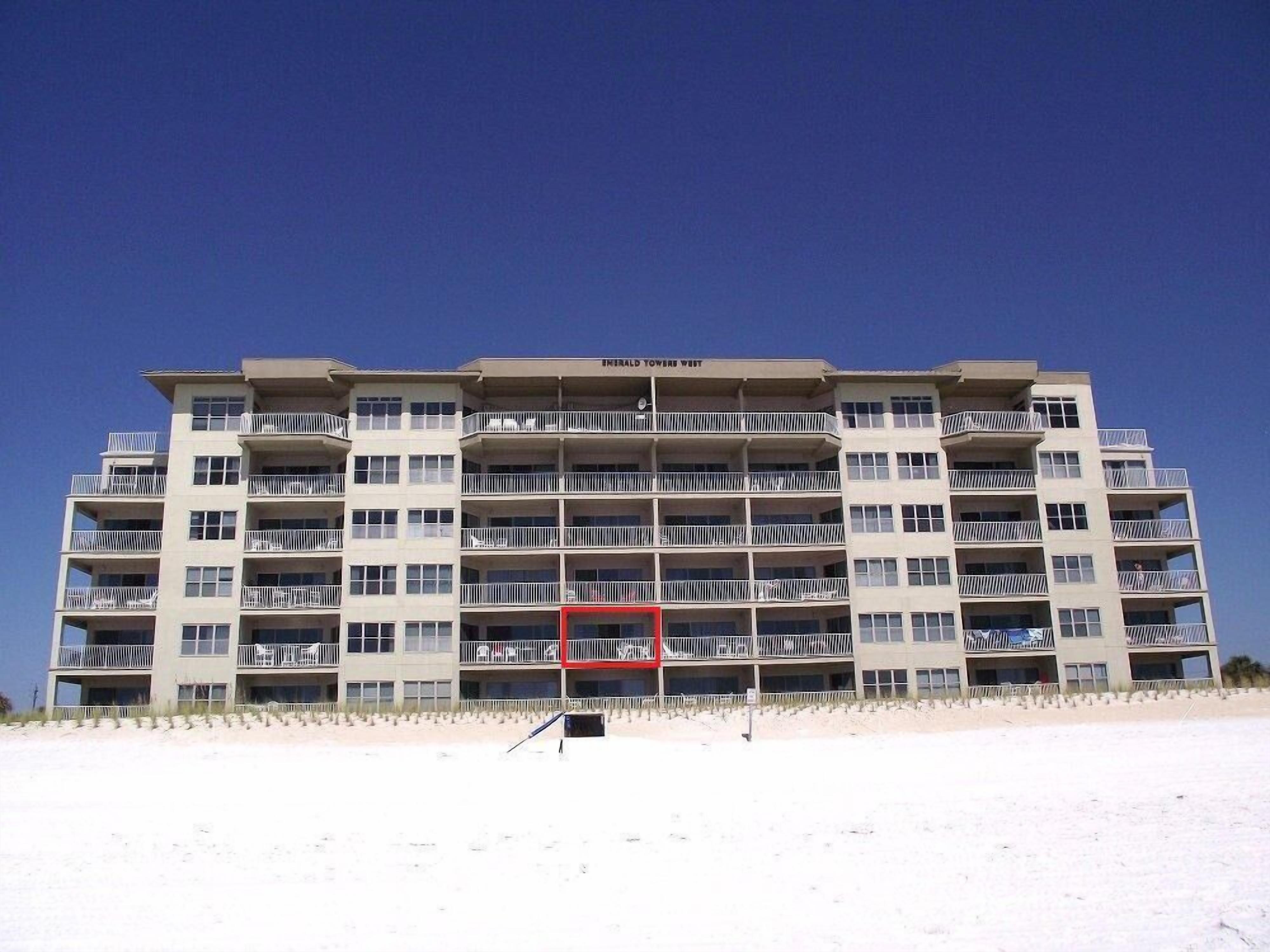 Un hôtel à plusieurs étages, doté de balcons, situé sur une plage.