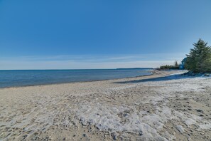 Una platja amb cel clar, sorra daurada i un edifici blau.