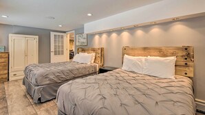 Une chambre avec deux lits, une tête de lit en bois et une porte donnant sur une autre pièce.