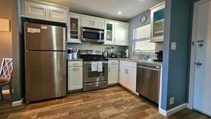 A modern kitchen with stainless steel appliances, white cabinets, and a herringbone wood floor. - Condo # 102 Perfect 2 bedroom one bath condo directly across from  famous Siesta Key Beach. (Sarasota)